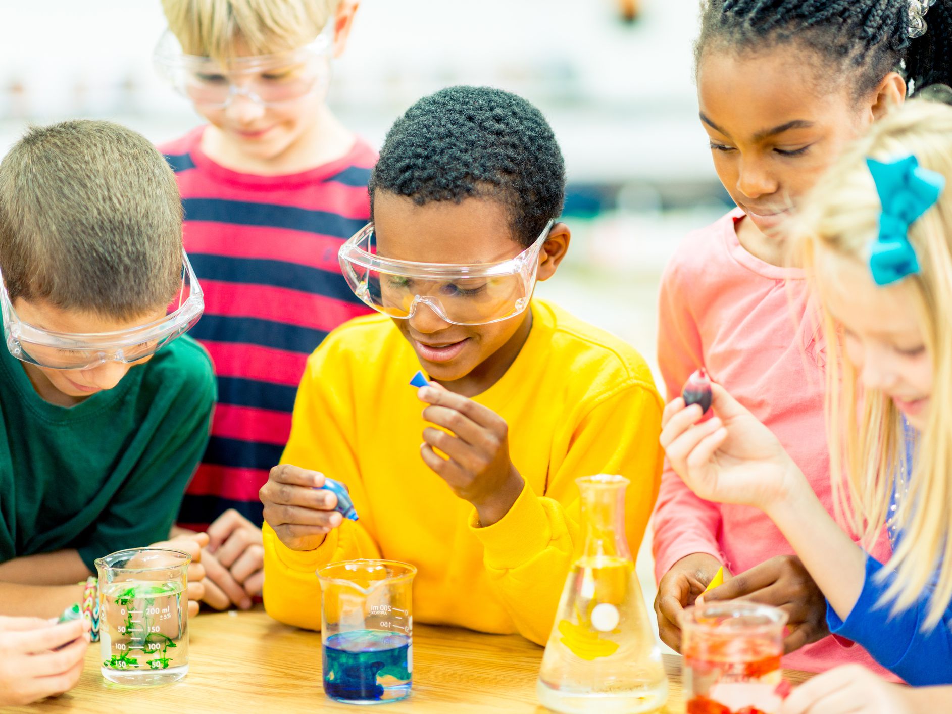 A multicultural group of children conduct a science experiment.