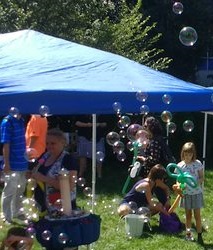 Families party outside in the library's Welcome Garden under a blue tent.