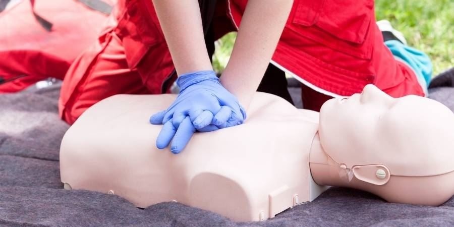 Photo of person's hands doing chest compressions on dummy.