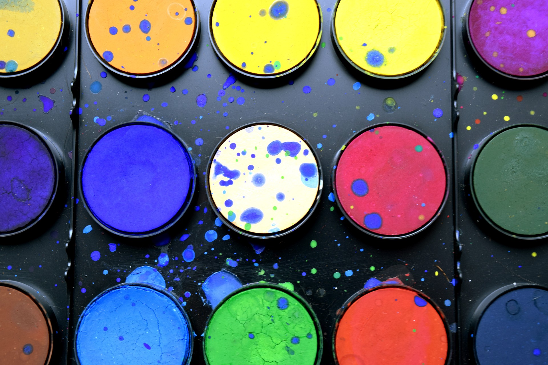 A set of water color paints, splattered with paint.