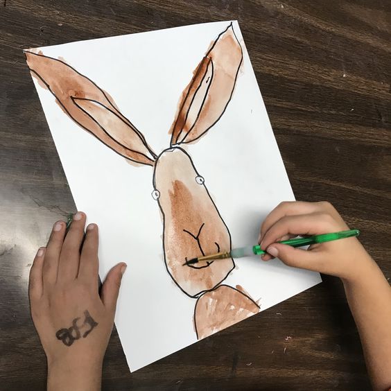 a child painting a picture of a brown bunny
