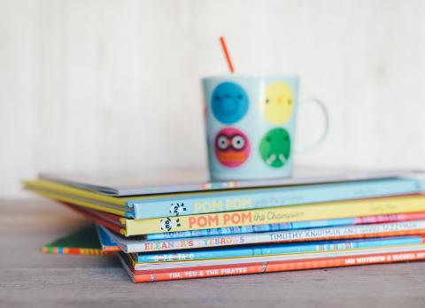 Stack of children's books with cup on top