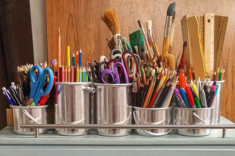 Cups of art supplies including pencils, paintbrushes, and scissors.