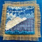 A fabric square with various stitches in blue and white.