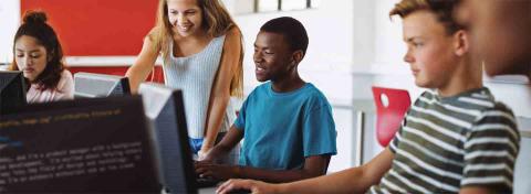 A multicultural group of teens sitting at computers.