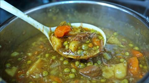 Photo of ladle and pot of hearty stew.