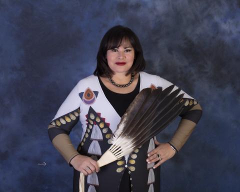 American Indian woman wearing posing with a fan.