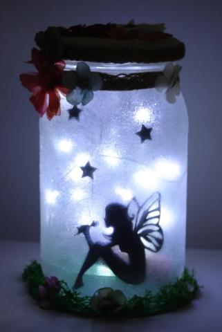 A glass jar with fairy silhouette and lights.