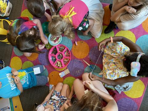 A group of children gather around art supplies