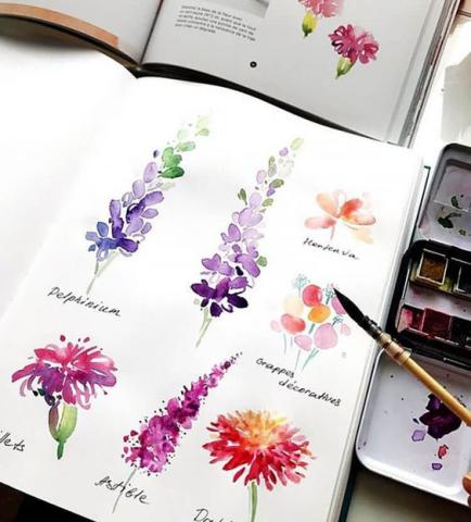 a variety of flowers painted with watercolors on a page in a sketchbook