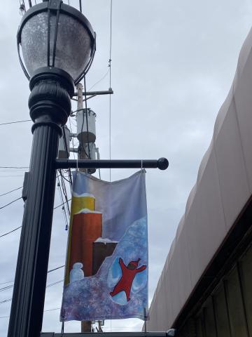 A banner painted with a scene from A Snowy Day hangs on a lightest