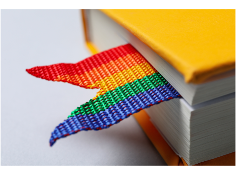 A closeup photo of a yellow book with a rainbow bookmark