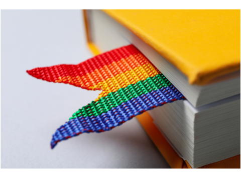 A close up photo of a yellow book with a rainbow bookmark.