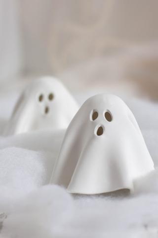 A photograph of two small, white ghost sculptures.