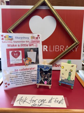 Photo of 2 mini canvases: one of Mishka the Therapy Dog, the other of The Little Prince. Love Your Library sign in background