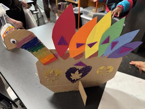 A turkey created by a young artist features construction paper features on a cardboard body.