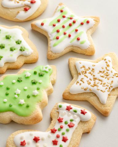 Iced and decorated holiday cookies lay on a white table.