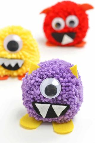 Yarn pom moms have google eyes and felt glued to them so they look like little monsters.