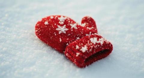 A red mitten is laying in the snow.