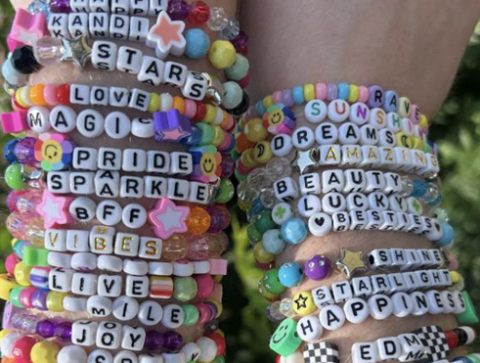 Photo of two arms full of beaded bracelets with words and phrases