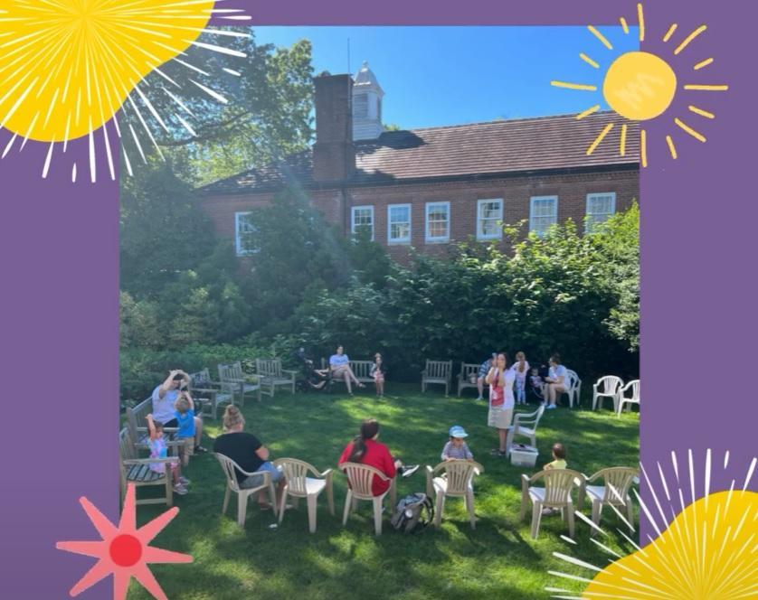 A picture of children and parents listening to a storytime outside.