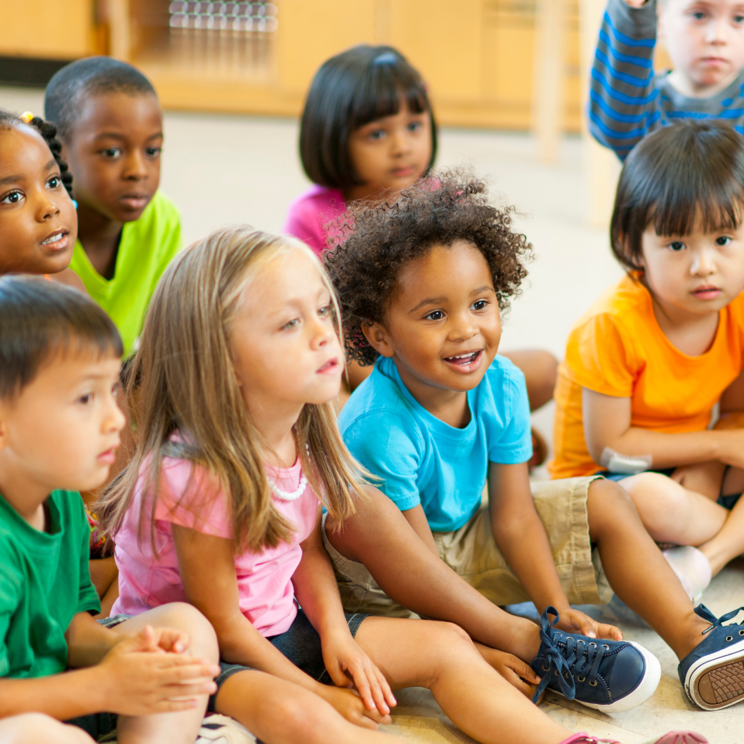 A group of diverse children listen to a story.