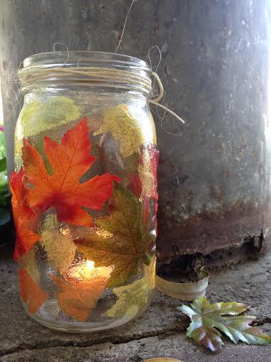 A mason jar covered in autumn leaves.