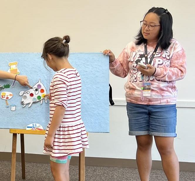 Miss CC helps kids add colorful spots to a white dog.