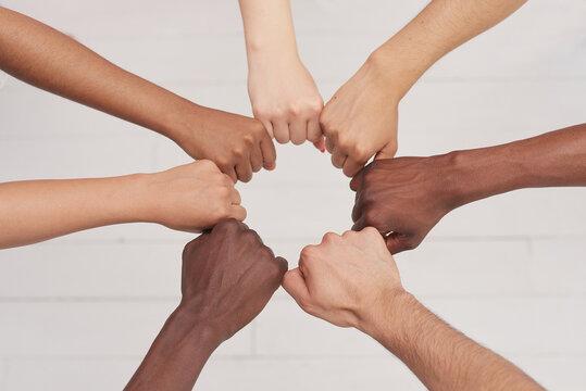 Photo of hands making circle. Skin tones are diverse.