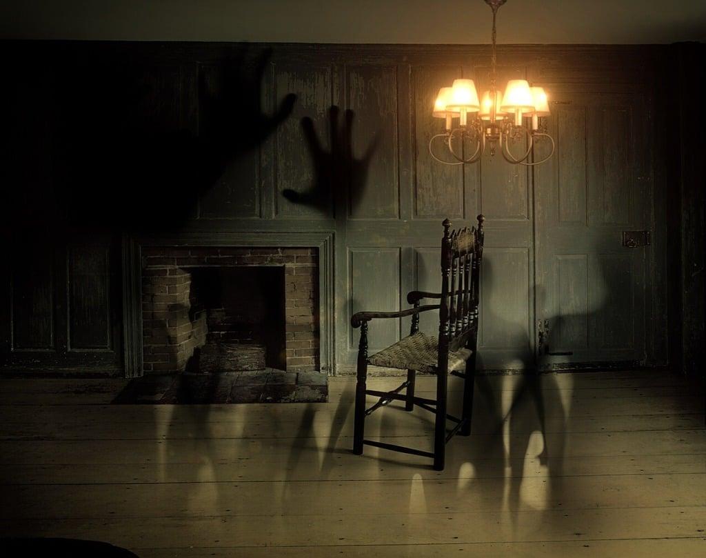 Image of abandoned room with hanging light and ghostly shapes