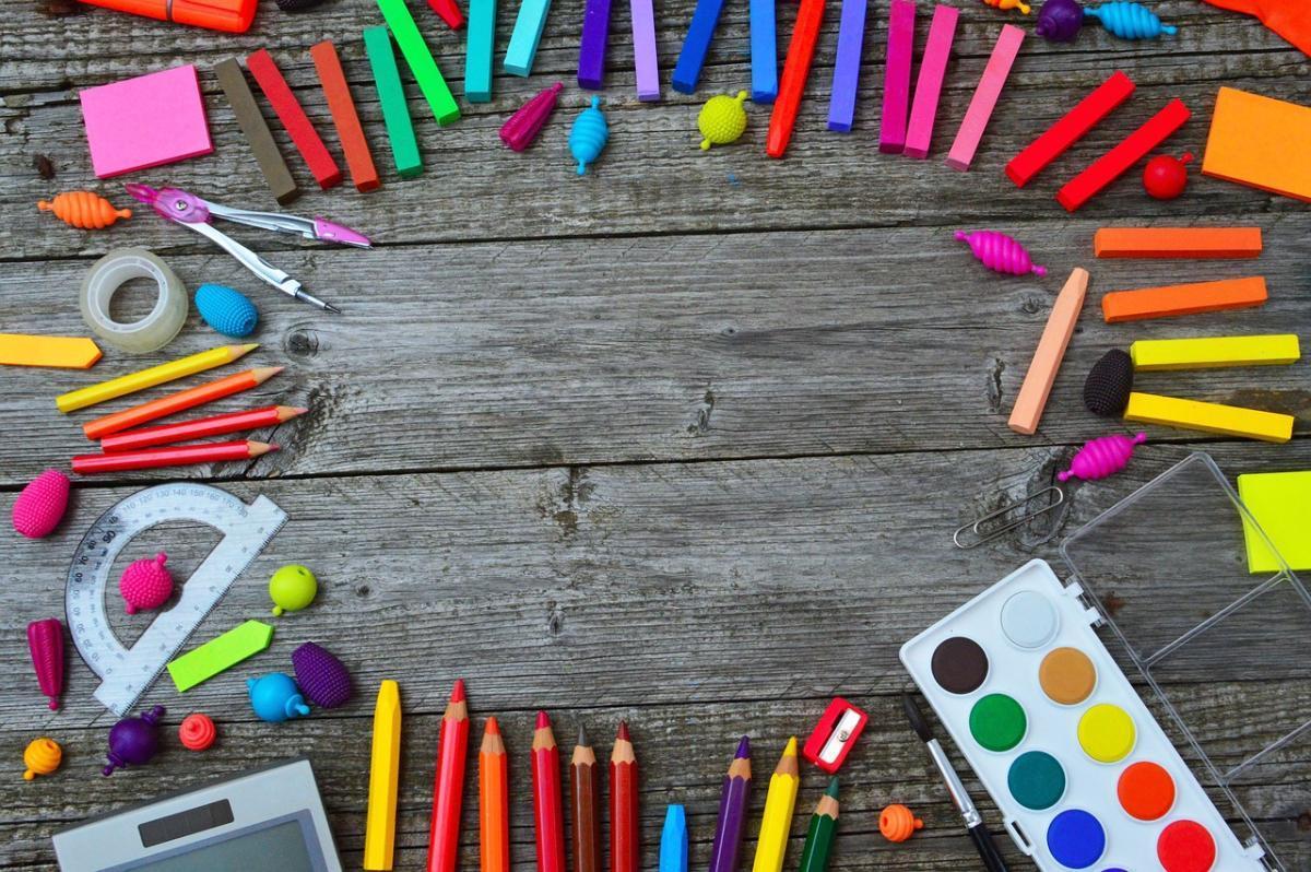 A photo of art supplies scattered in a circle on a wooden table.