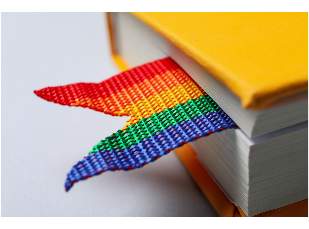A close up photo of a yellow book with a rainbow bookmark.