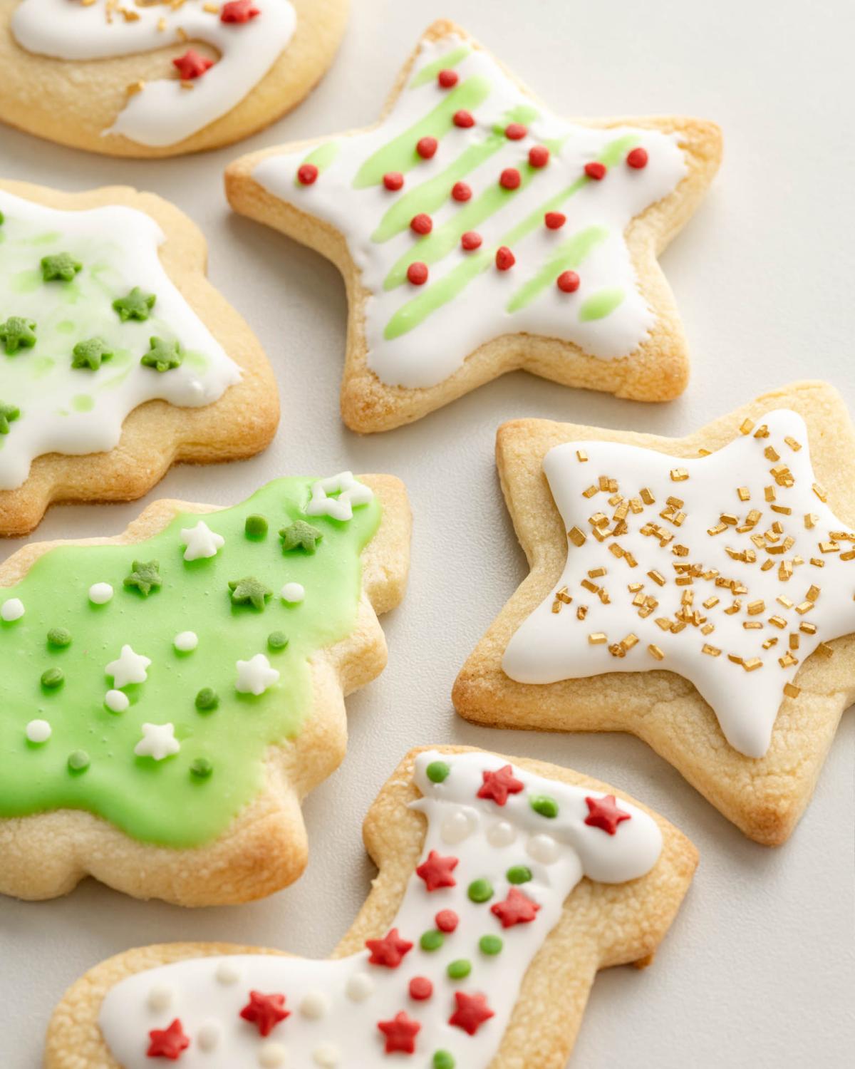 Iced and decorated holiday cookies lay on a white table.