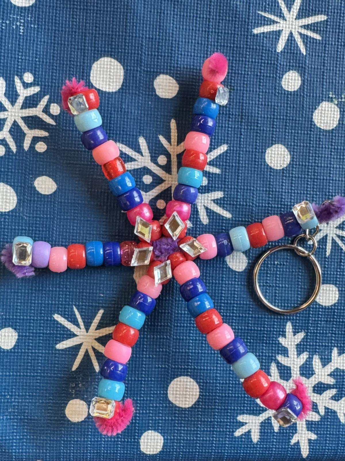 A beaded snowflake keychain is made with beads, pipe cleaners and gems.