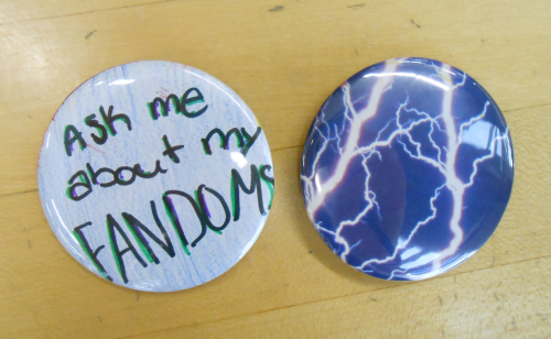 Photo of DIY buttons - one says "Ask me about my fandoms," the other has colorful lightning